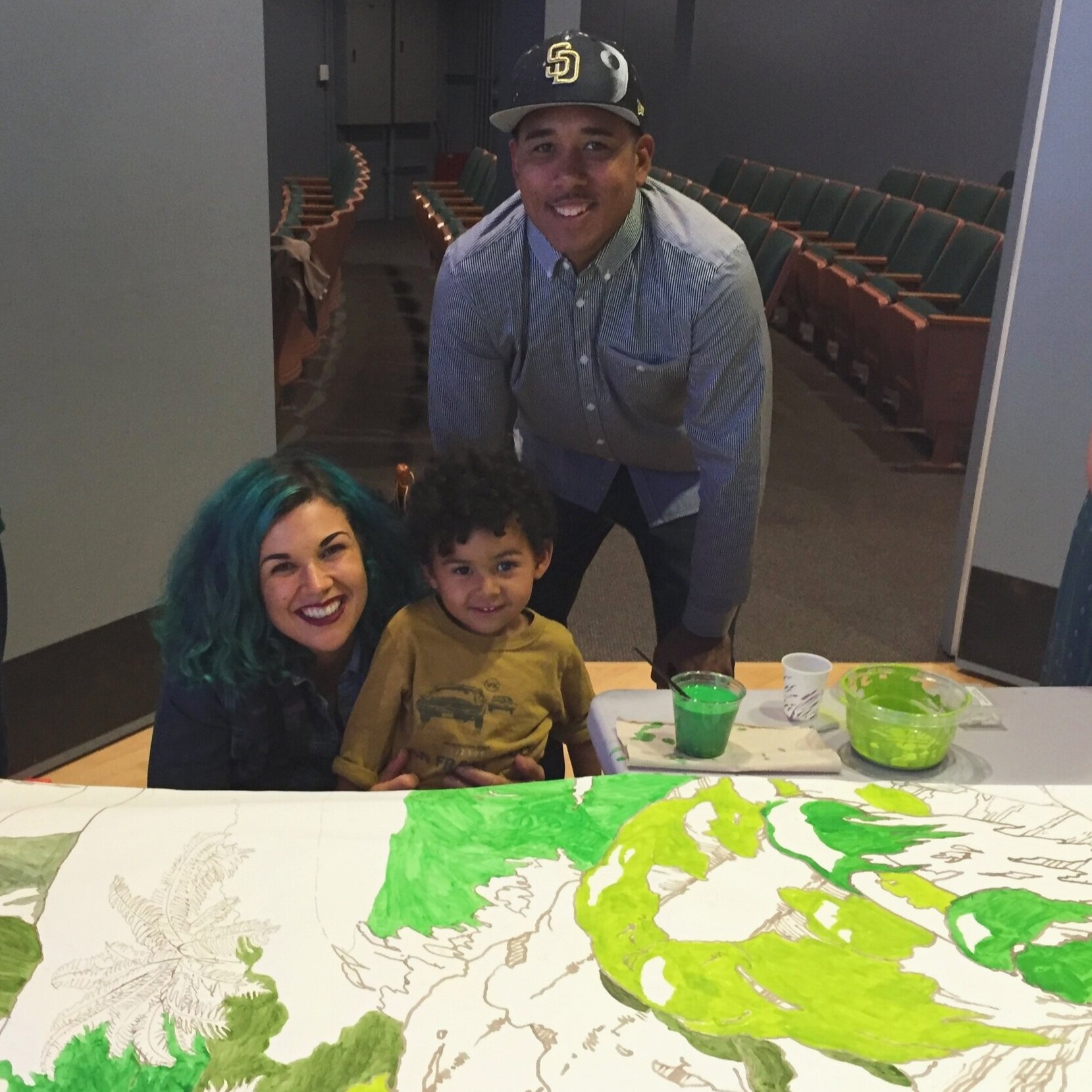 A family dabbles in green at a First Friday community mural-painting night.