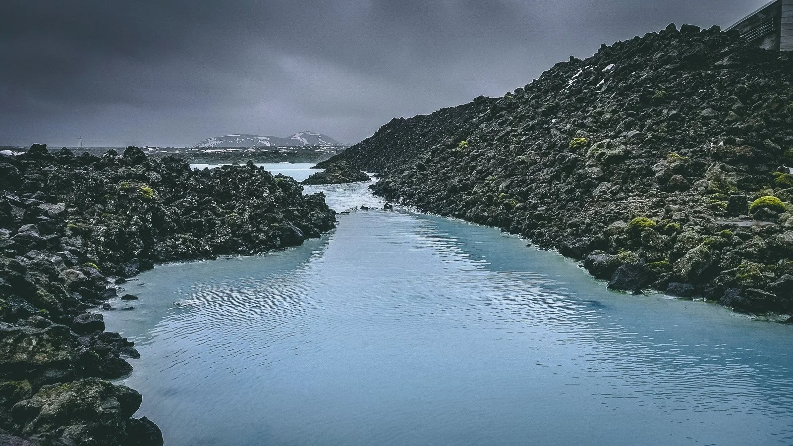 Milky blue geothermal water between black lava rocks at the Blue Lagoon in Iceland