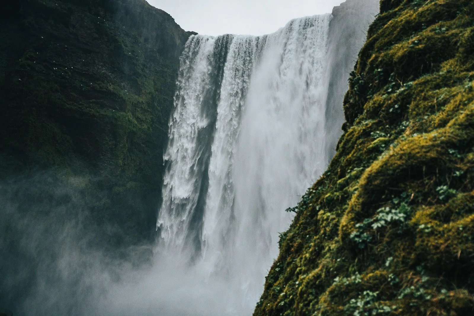 Close view of Skógafoss waterfall framed by a moss-covered cliff in Iceland