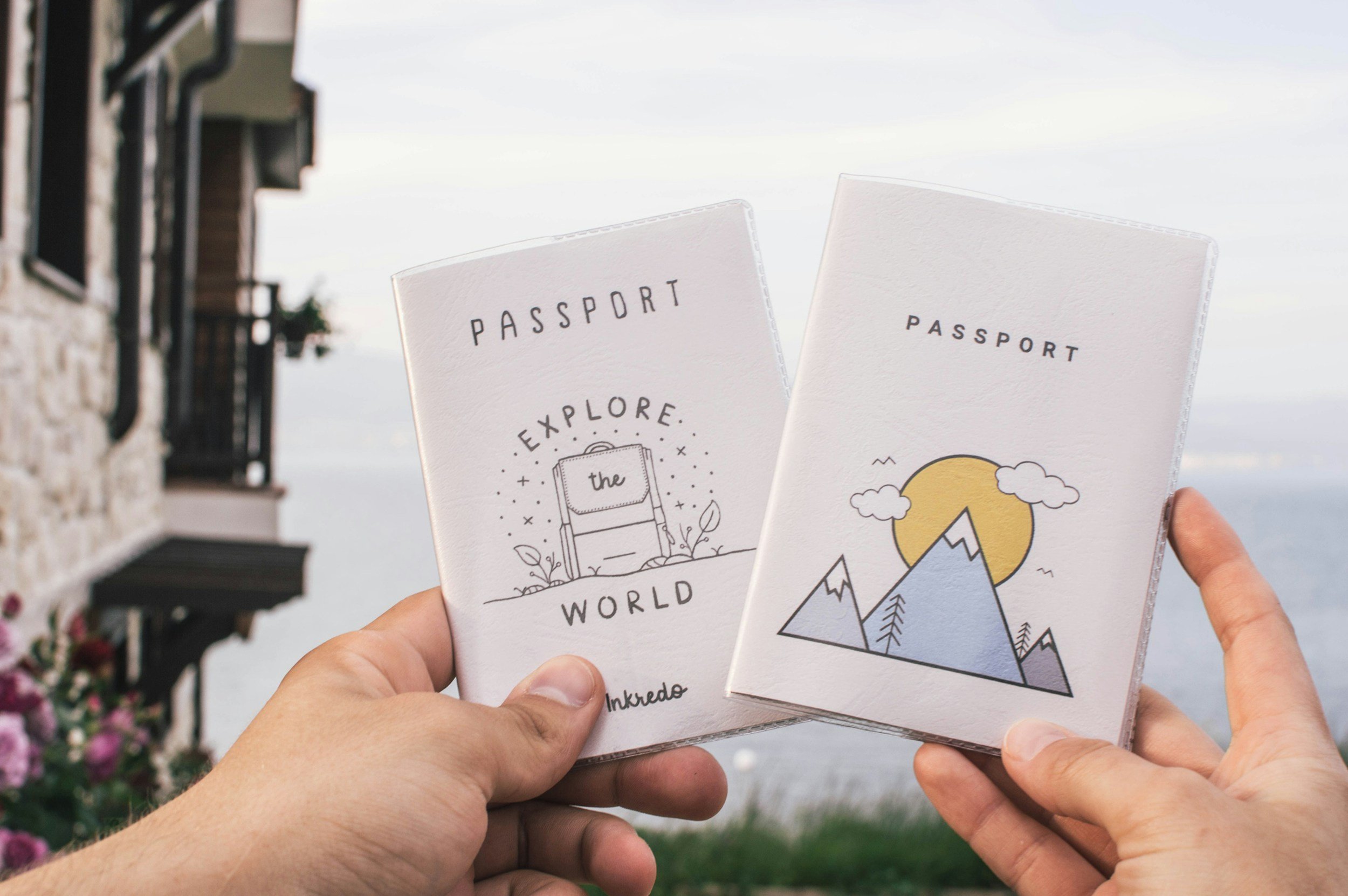 Two passports in decorative travel covers held up outdoors