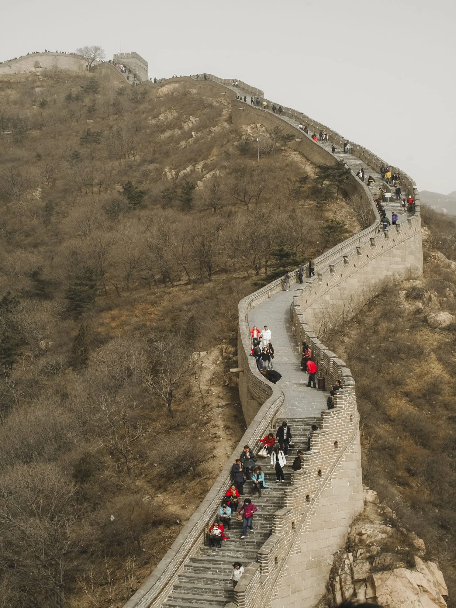 Great Wall of China climbing a steep hillside with visitors walking toward a watchtower