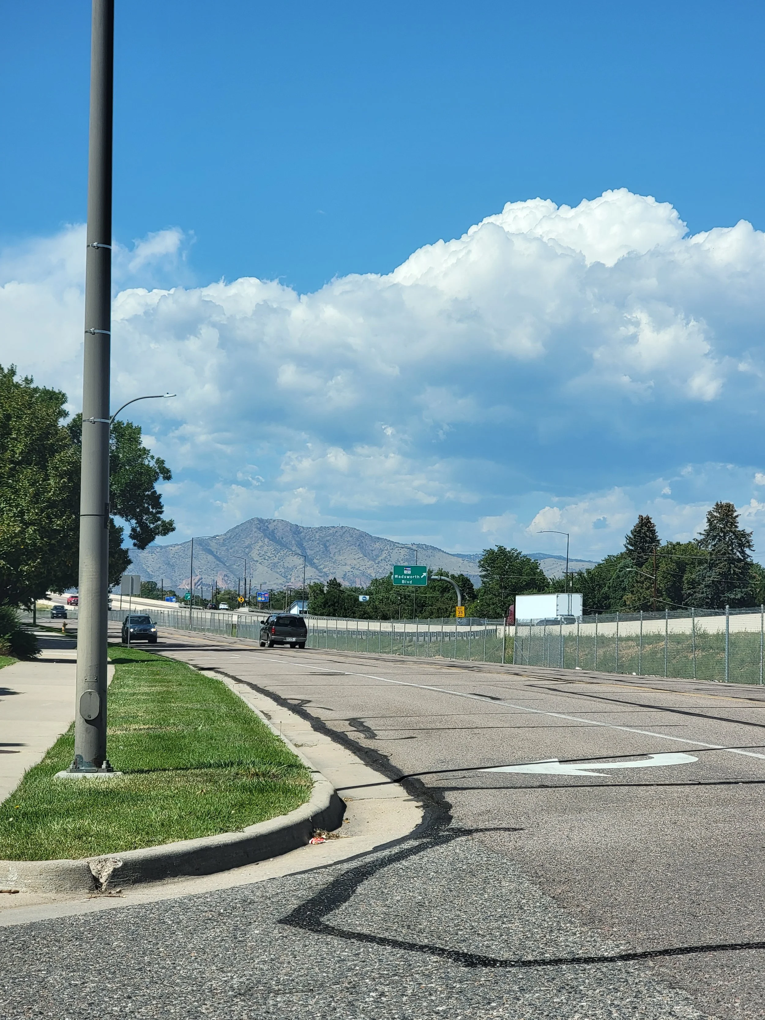 wide open street with grass lined side walks and a mountain range in the background