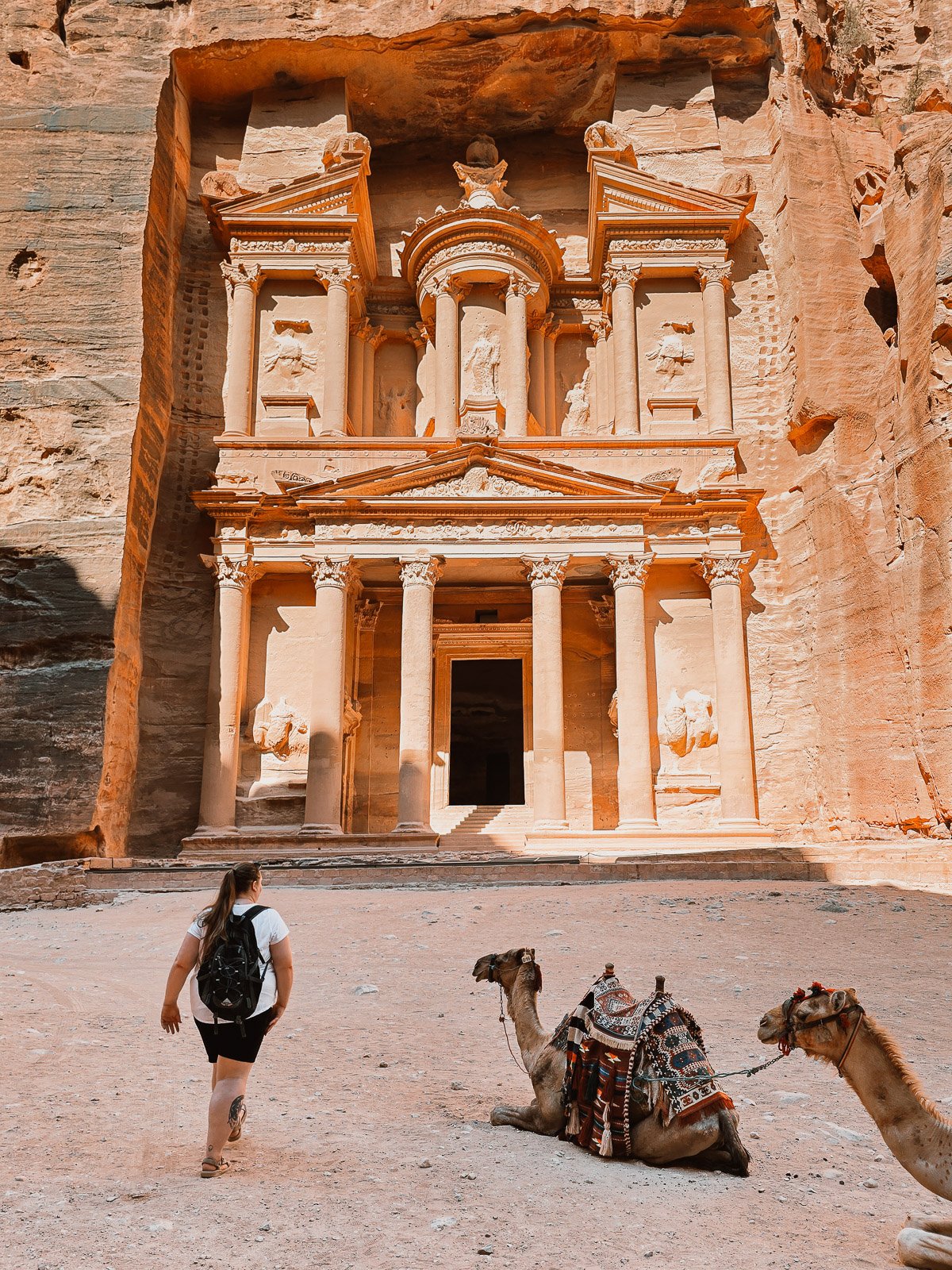 Traveler walking toward the Treasury at Petra with camels in the foreground