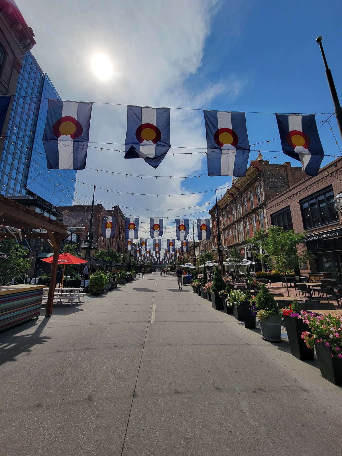 Pedestrian area of Larimer Square in Denver lined with Colorado flags and restaurant patios