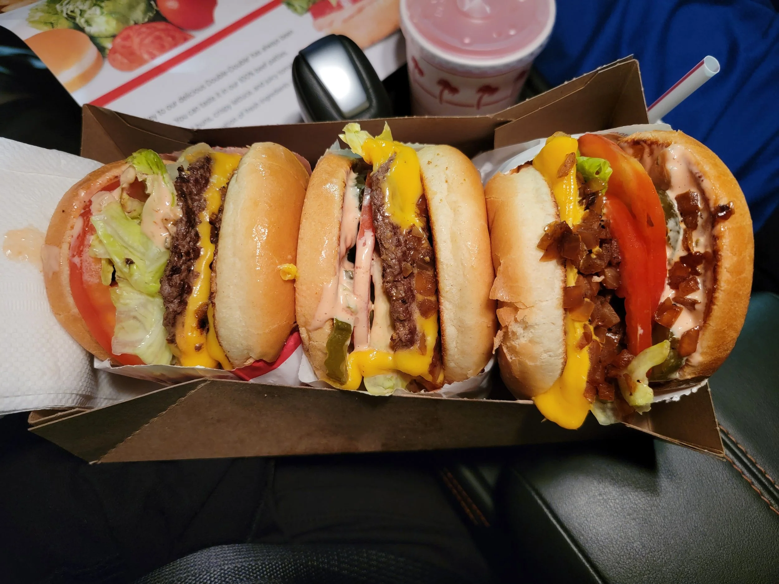 three In-N-Out cheese burgers with multiple toppings animal stylein a cardboard box