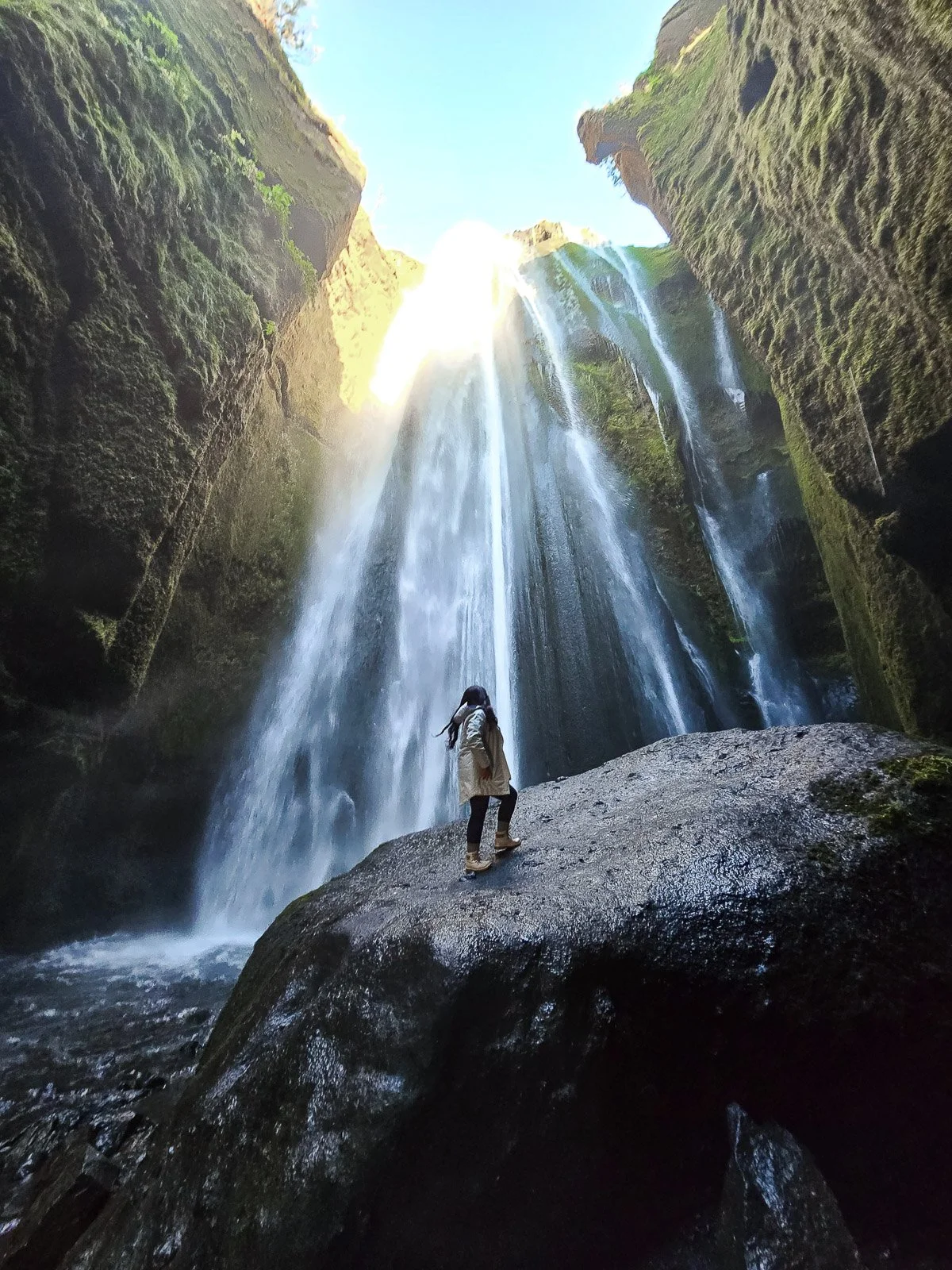 Traveler standing inside the narrow gorge beneath Gljúfrabúi waterfall in Iceland