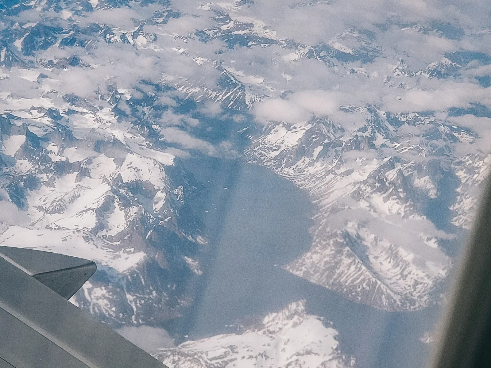 View from an airplane window over snow-covered mountains in Iceland