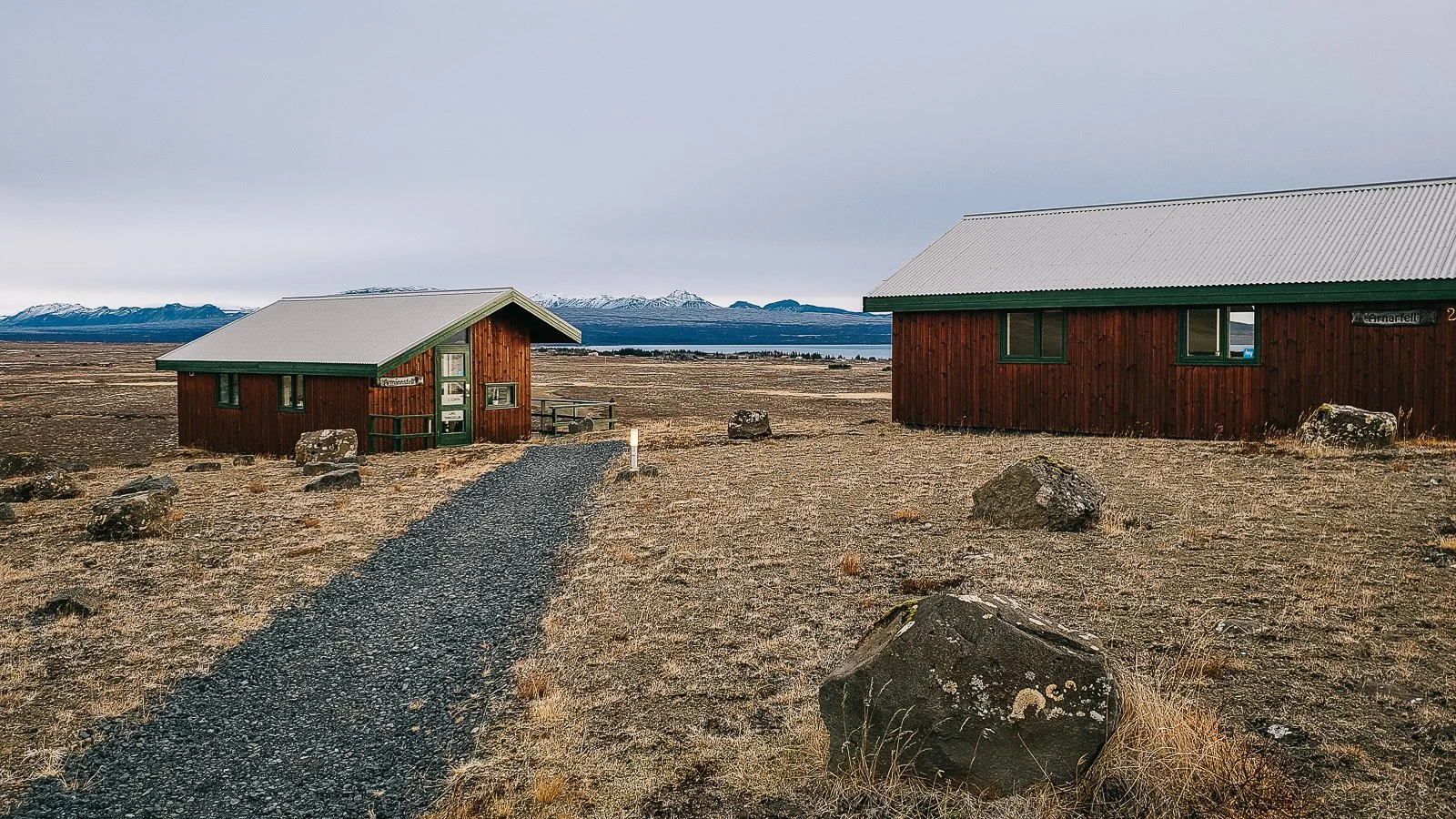 Wooden cabins in a rural Icelandic landscape with mountains in the distance