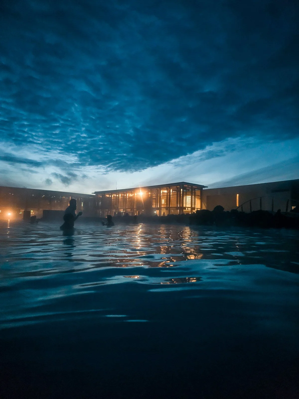 Blue Lagoon geothermal pool at dusk with people bathing beneath a dark blue sky