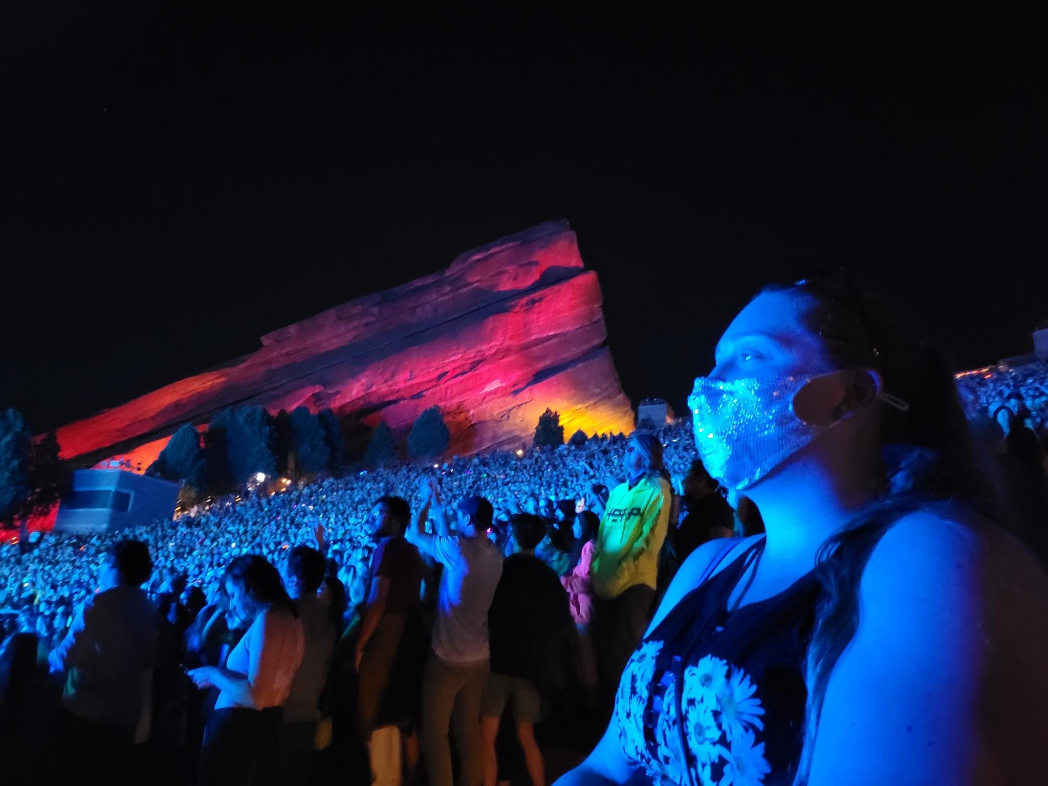 woman with sequined mask on watching a concert at red rocks amphitheater at night