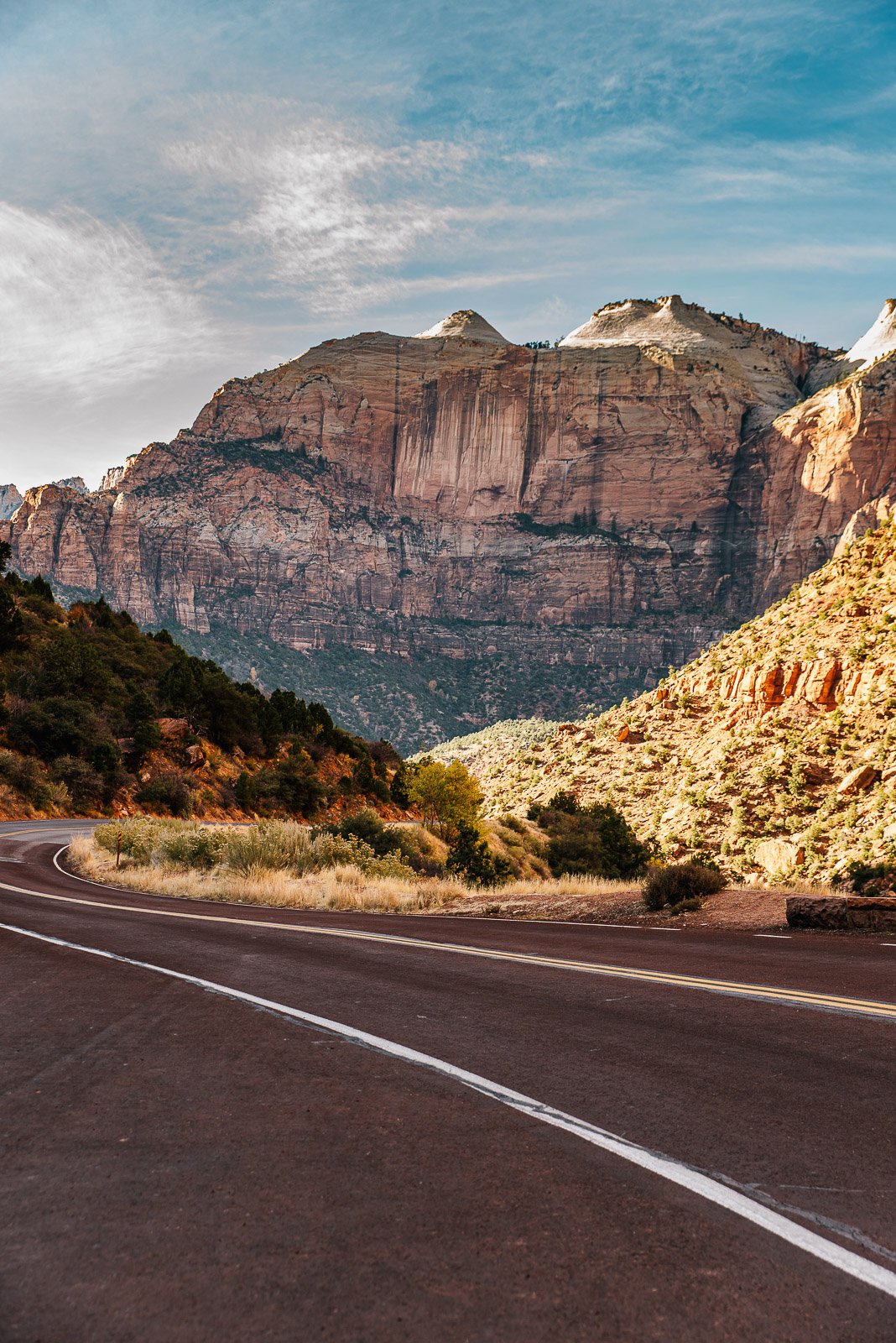 Scenic road winding beneath massive sandstone cliffs in Utah.