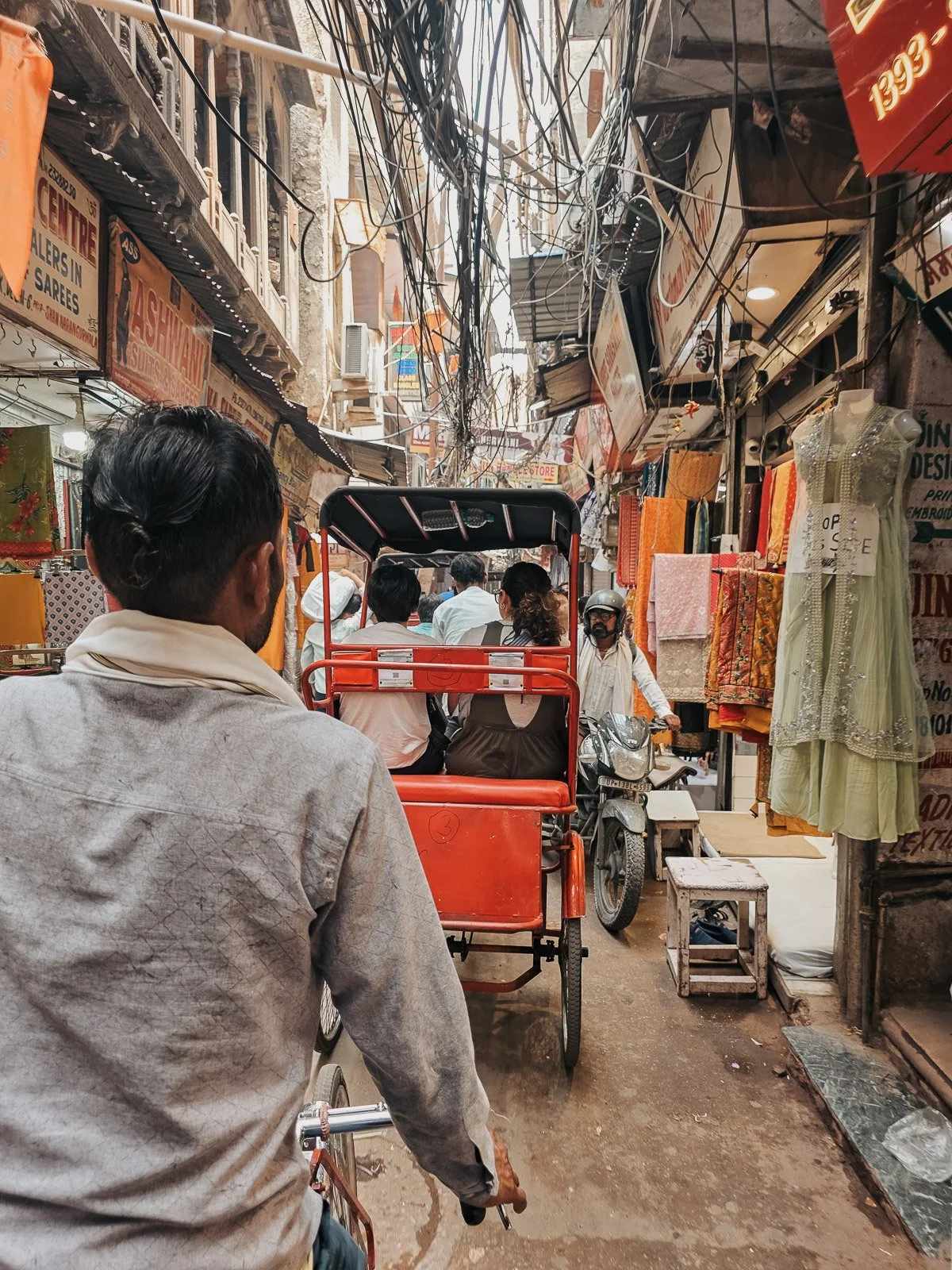 Busy market street in India with shops and a tuk-tuk traveling through the narrow road