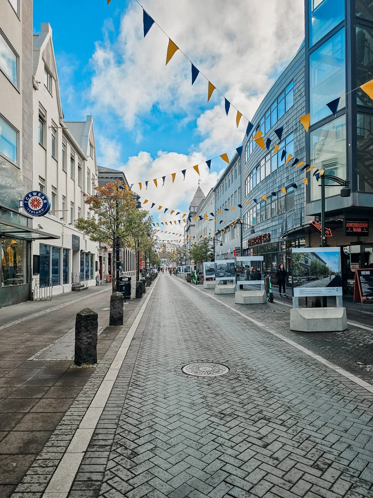 Pedestrian street lined with shops and colorful flags in downtown Reykjavík, Iceland