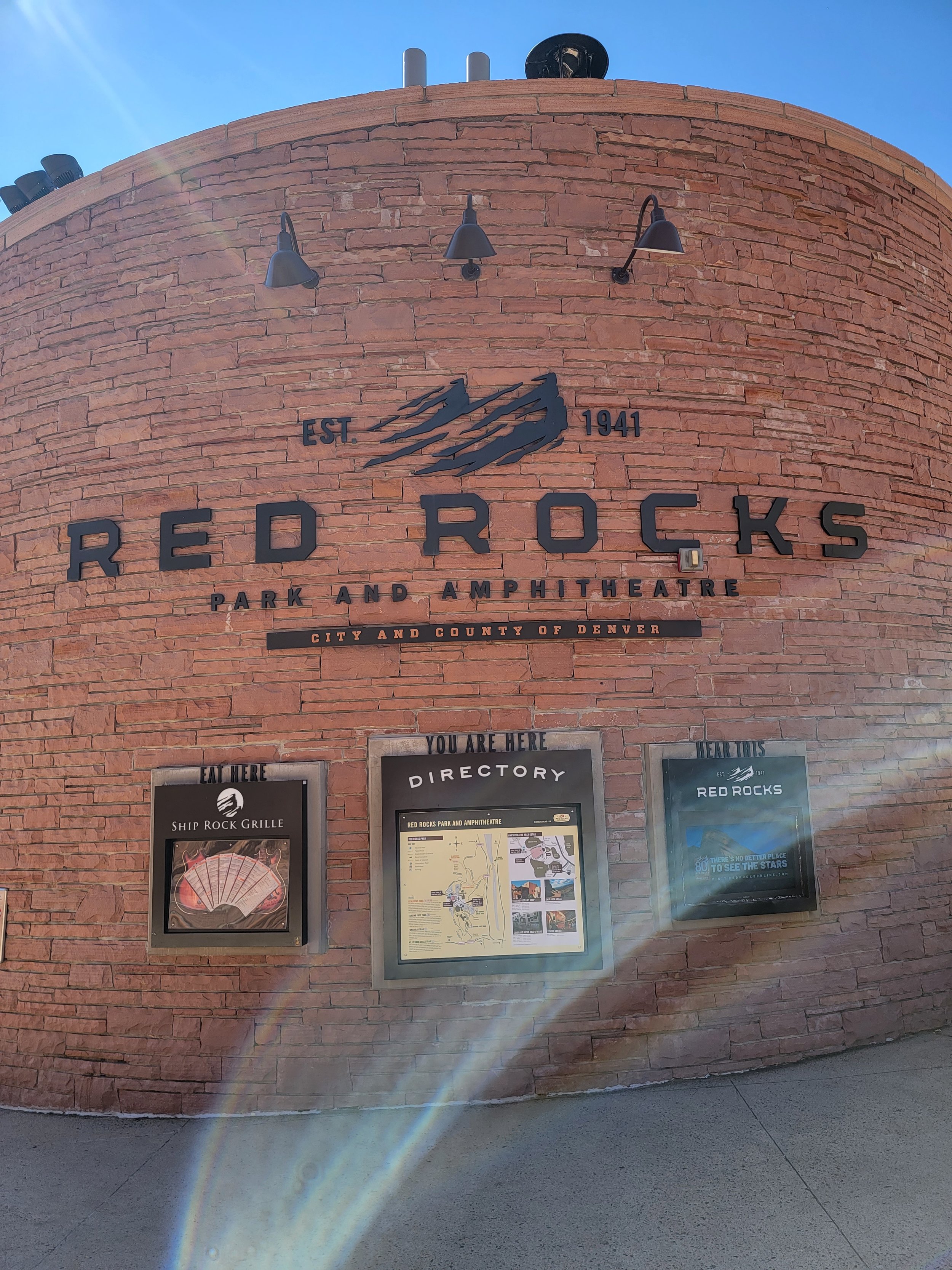 large brick wall with the words red rocks amphitheater and other signs hung below