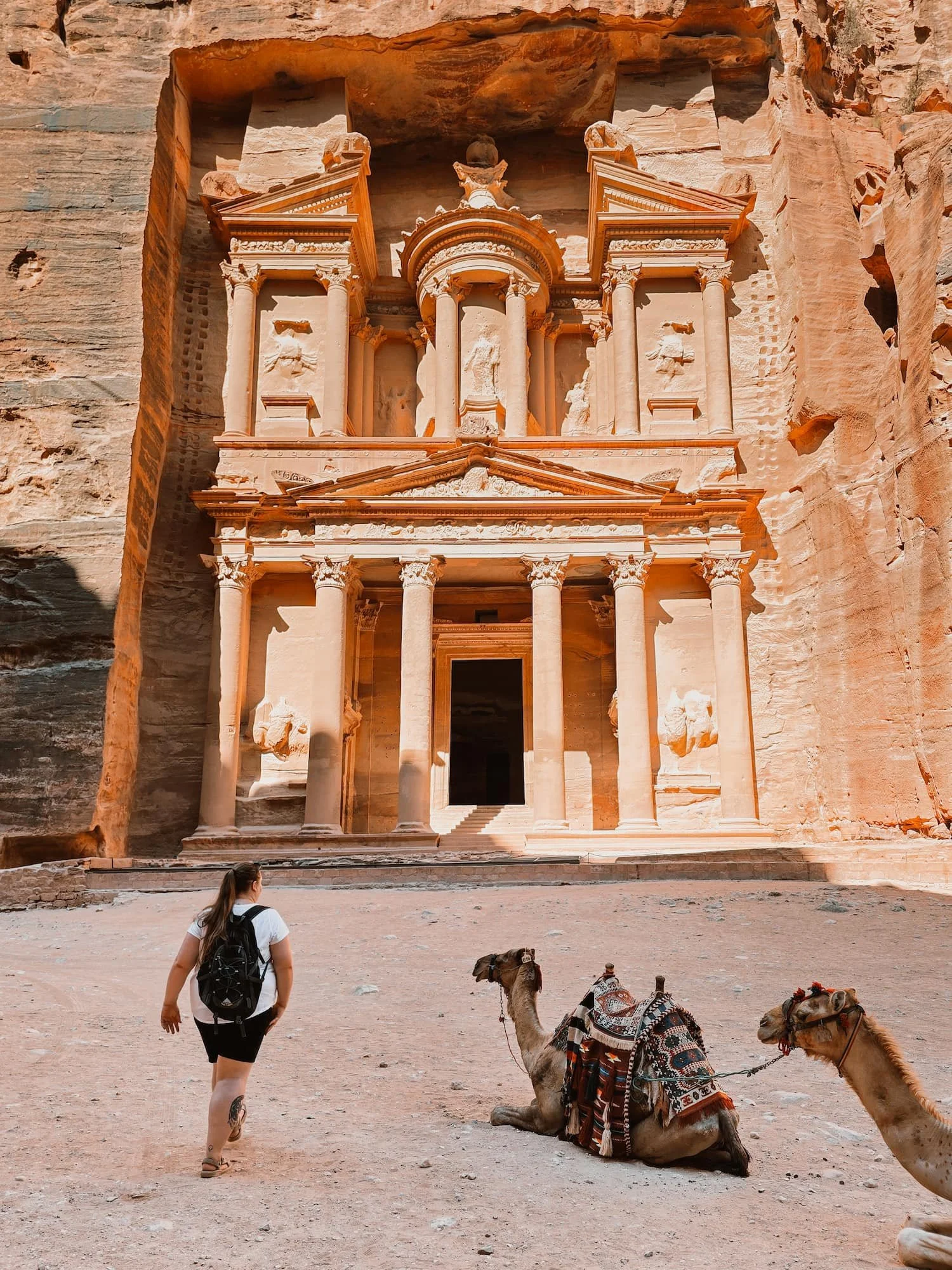 Traveler walking toward the Treasury at Petra with camels resting in front