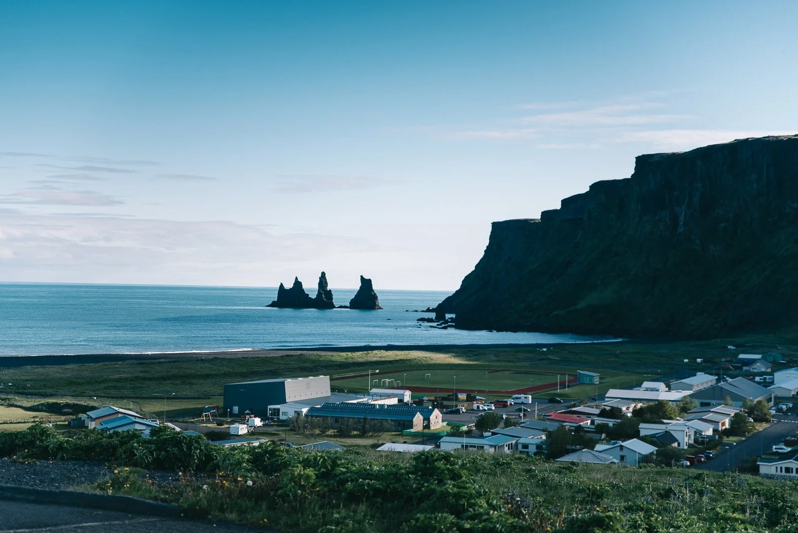 Village of Vík with Reynisdrangar sea stacks and the Icelandic coastline in the distance