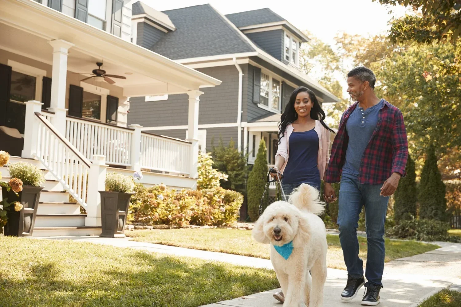 A couple walking their dog together outside their home