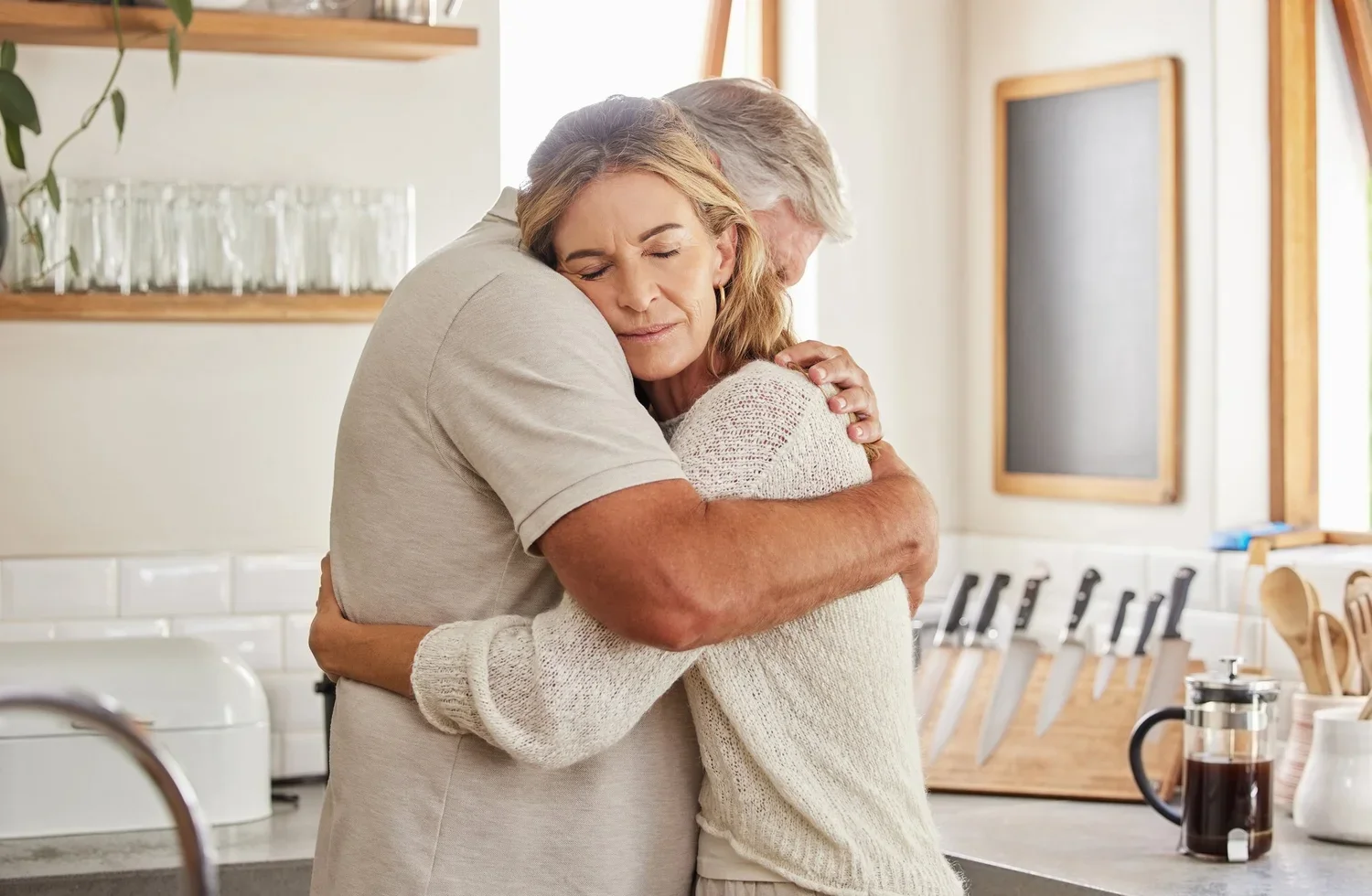An older couple holding each other tenderly in their kitchen