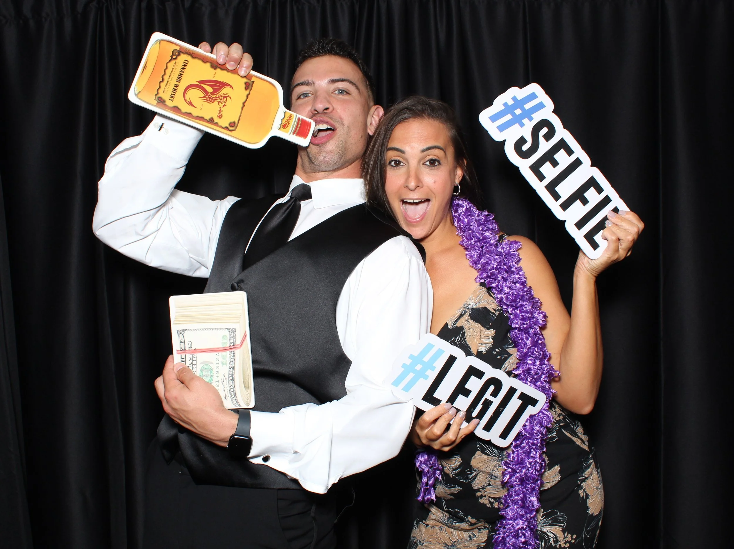 A photo booth strip with three images of a group smiling and posing with a hashtag sign '#SQUADGOALS'. The background features string lights and the bottom text reads 'Abby & Art 10/3/2021'. The frame has a rustic wooden design with leafy accents.