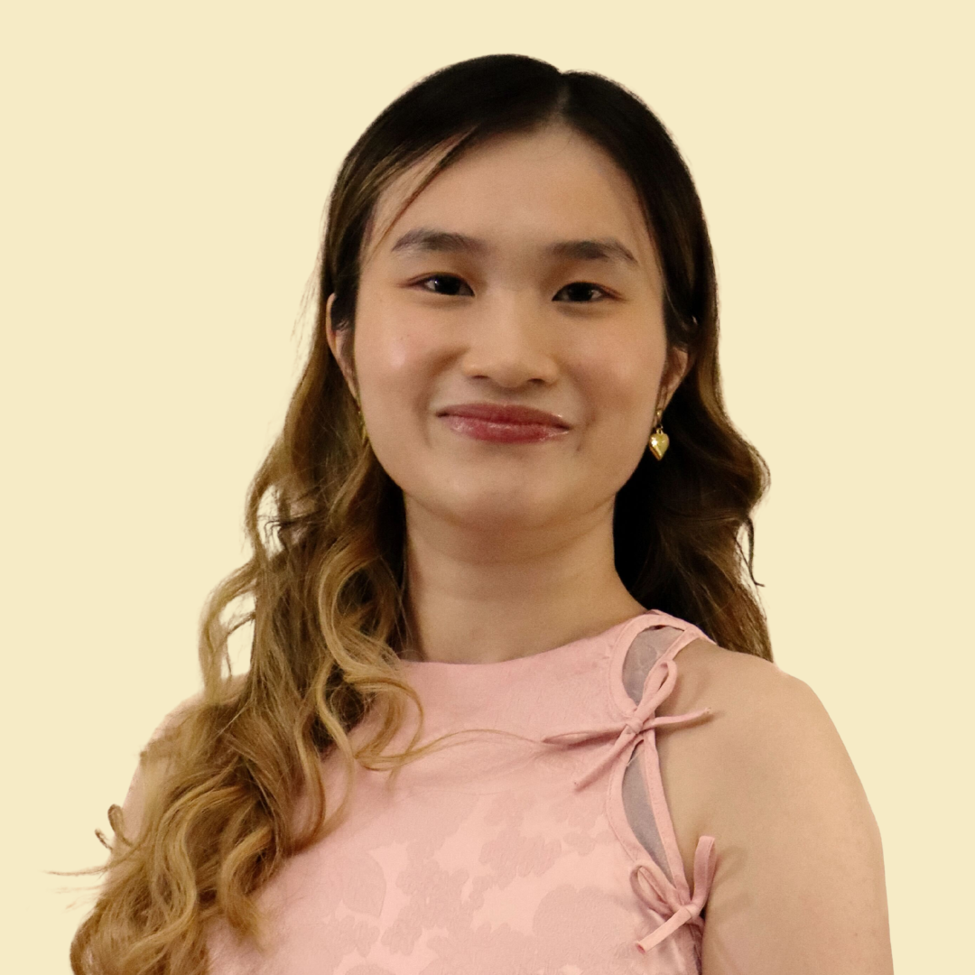 A smiling woman with brown to blonde hair, wearing a pink top, against a butter yellow background.