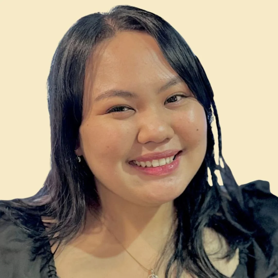 A smiling woman with black hair, wearing a black top and a necklace, against a butter yellow background.