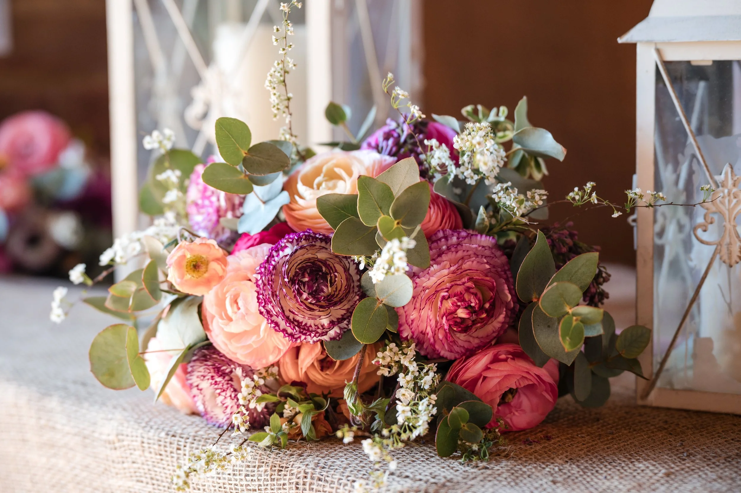 A colourful bridal bouquet example, including seasonal ranunculus, blossom, eucalyptus, geums and tulips