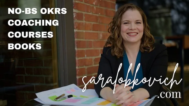 A photo of Sara sitting outdoors at a table covered in paper and sticky notes. .png
