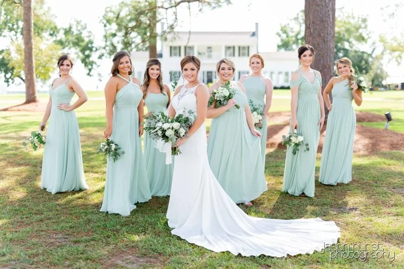 Bride and bridesmaids in blue dresses post for wedding photos at a luxury wedding venue near Savannah