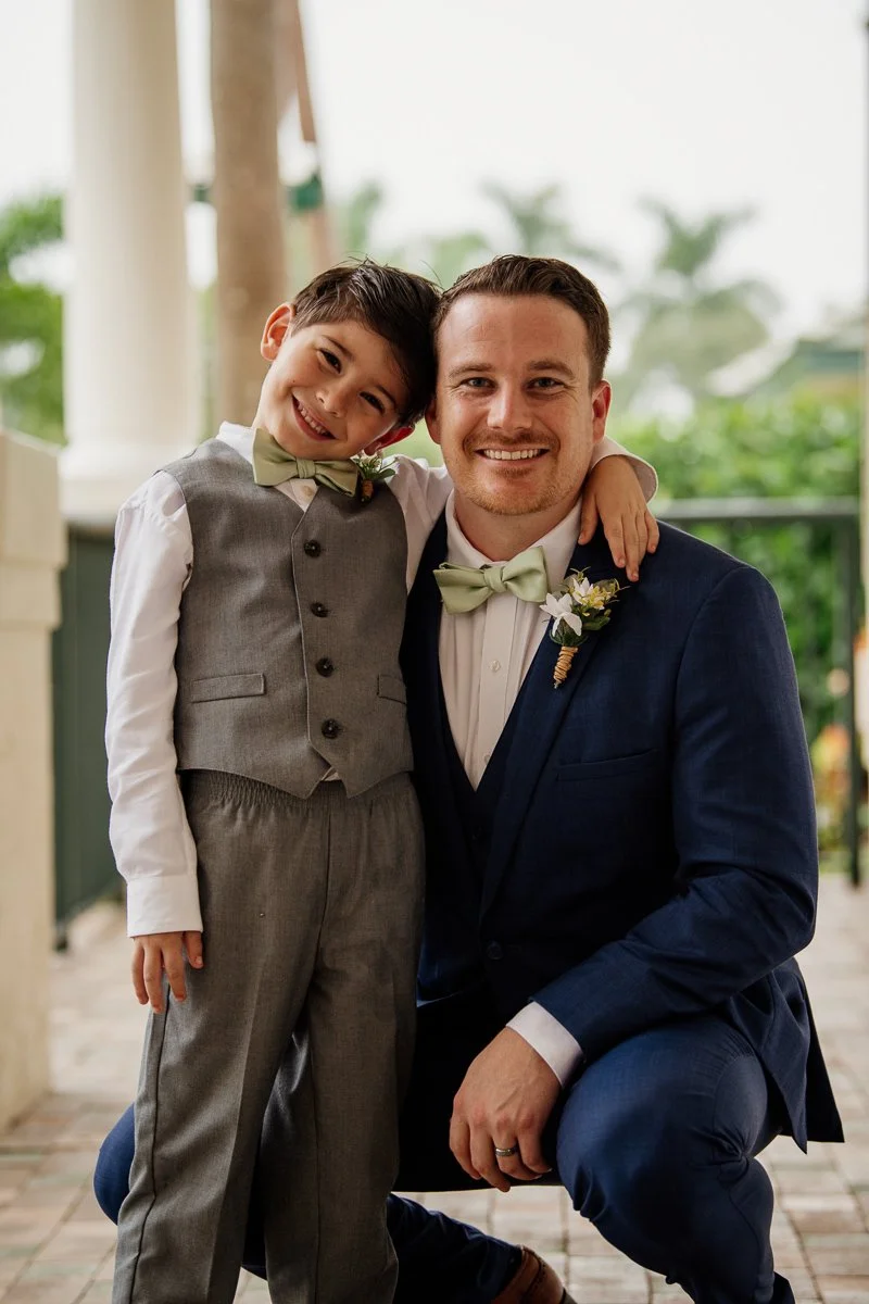 groomsman hugs the ring bearer and smiles