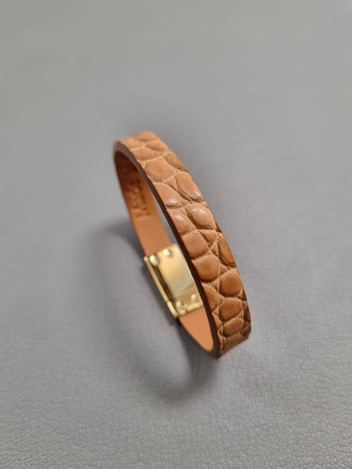 Angled view of a luxury cognac crocodile bracelet with a magnetic clasp, made by Pila Luxuria in Canada.
