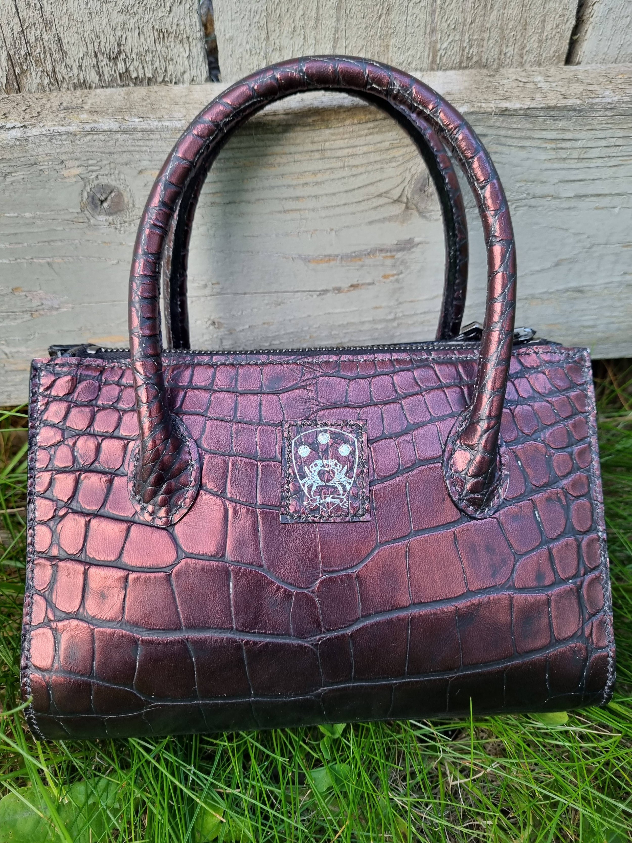 Front view of a luxury dark cherry alligator leather leather handbag, made by Pila Luxuria in Canada.
