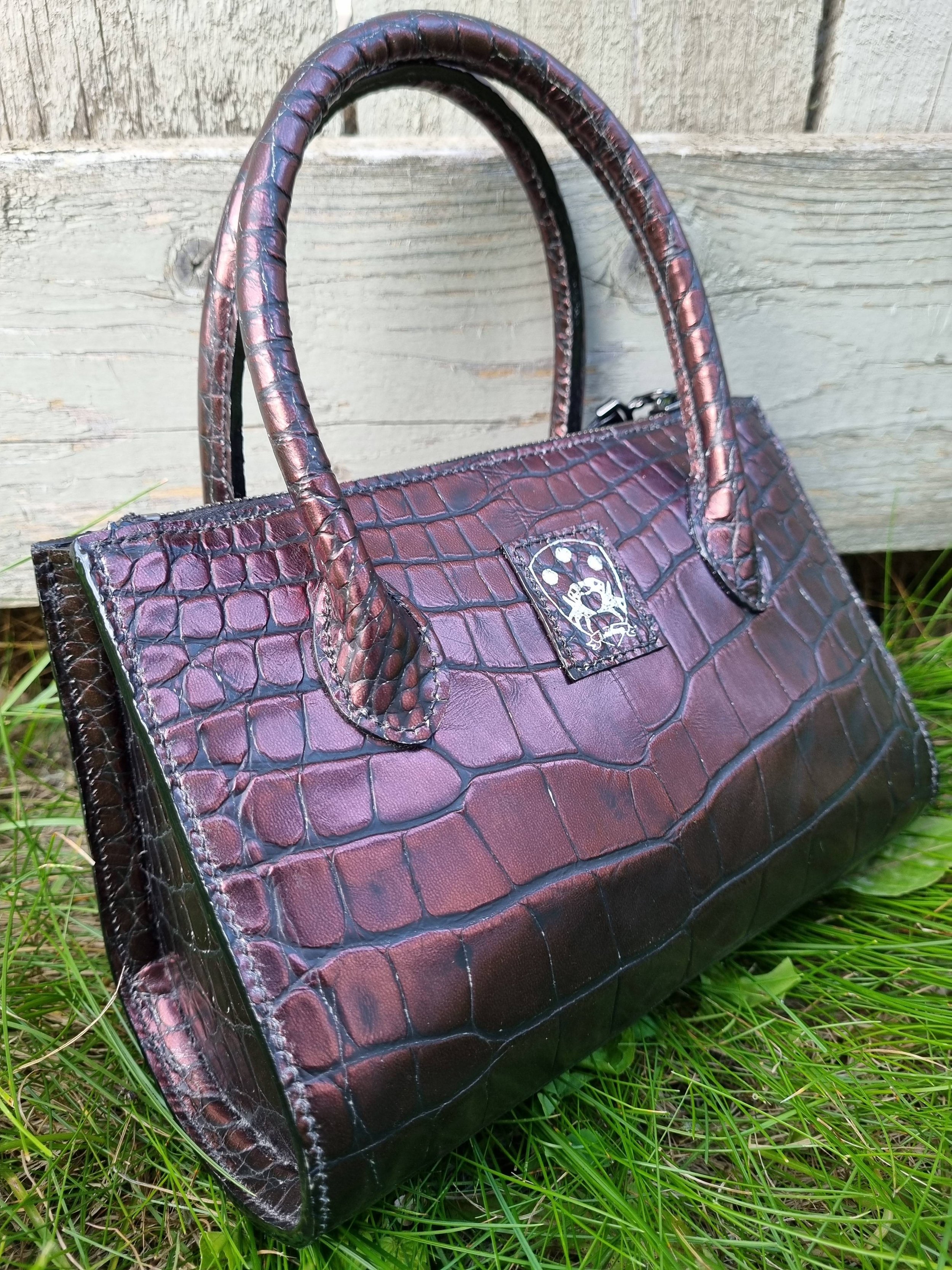 Angled view of a luxury dark cherry alligator leather leather handbag, made by Pila Luxuria in Canada.