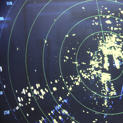 Image of a marine radar showing green circles and neon green radar images on a map