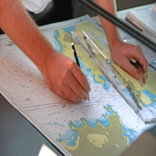 Nautical map with pencil and measuring tools being used by a sailor