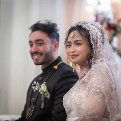 A bride and groom in wedding attire, smiling during their wedding ceremony.
