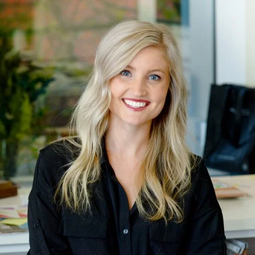 professional headshot of a smiling blonde woman with red lipstick wearing a black button up top
