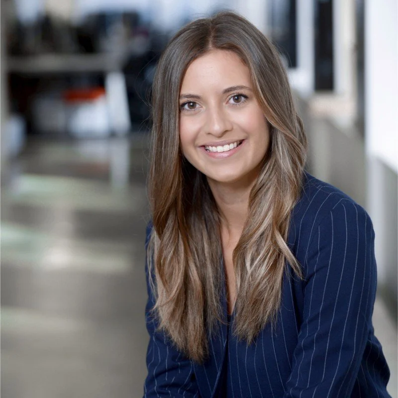 Smiling professional woman with brown hair wearing a pinstripe navy blazer