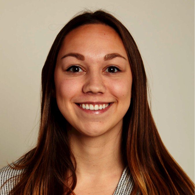 professional headshot of a smiling woman with brown hair on a tan background