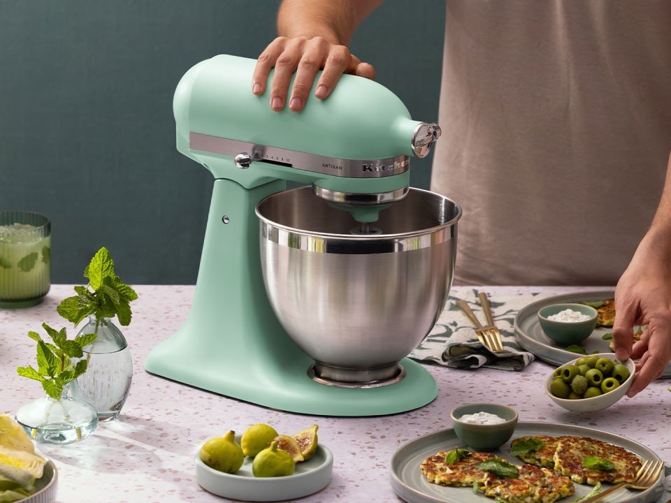 Roll Cut Studios campaign for KitchenAid Appliances Color of the Year. Lifestyle photograph by Huge Galdones of spearmint stand mixer to prepare food in a kitchen on a countertop with plates of food, figs, olives, and drinks nearby.