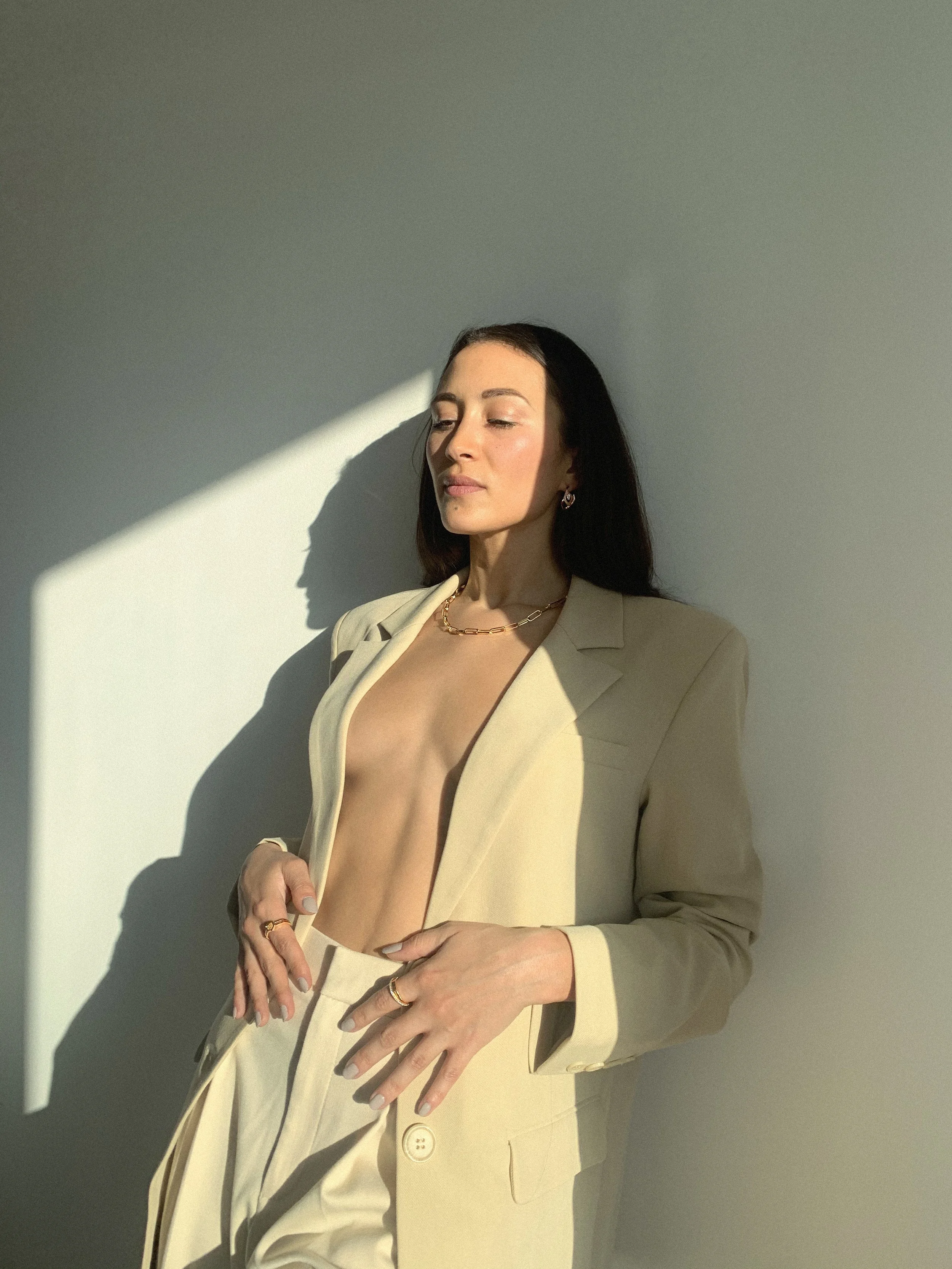 female model in 18k yellow gold vermeil Halo Ring, Orbit Signet Ring, Xavi Necklace and Coba Earrings with white diamonds in beige blazers and trousers EDXU London campaign