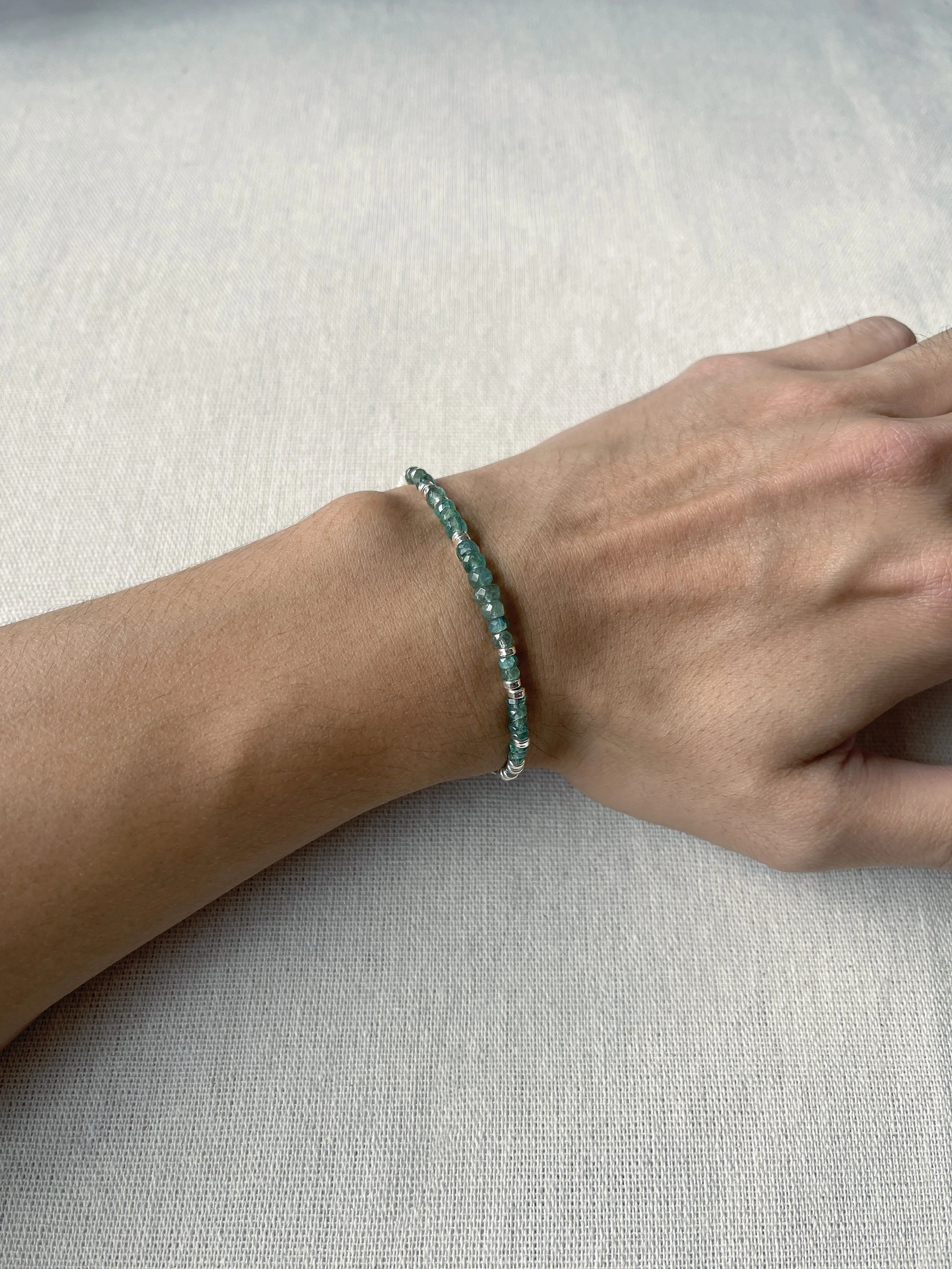 EDXU London still life photo of a male model wearing Pietra Emerald Bracelet in rhodium plated silver with rondelle emerald beads