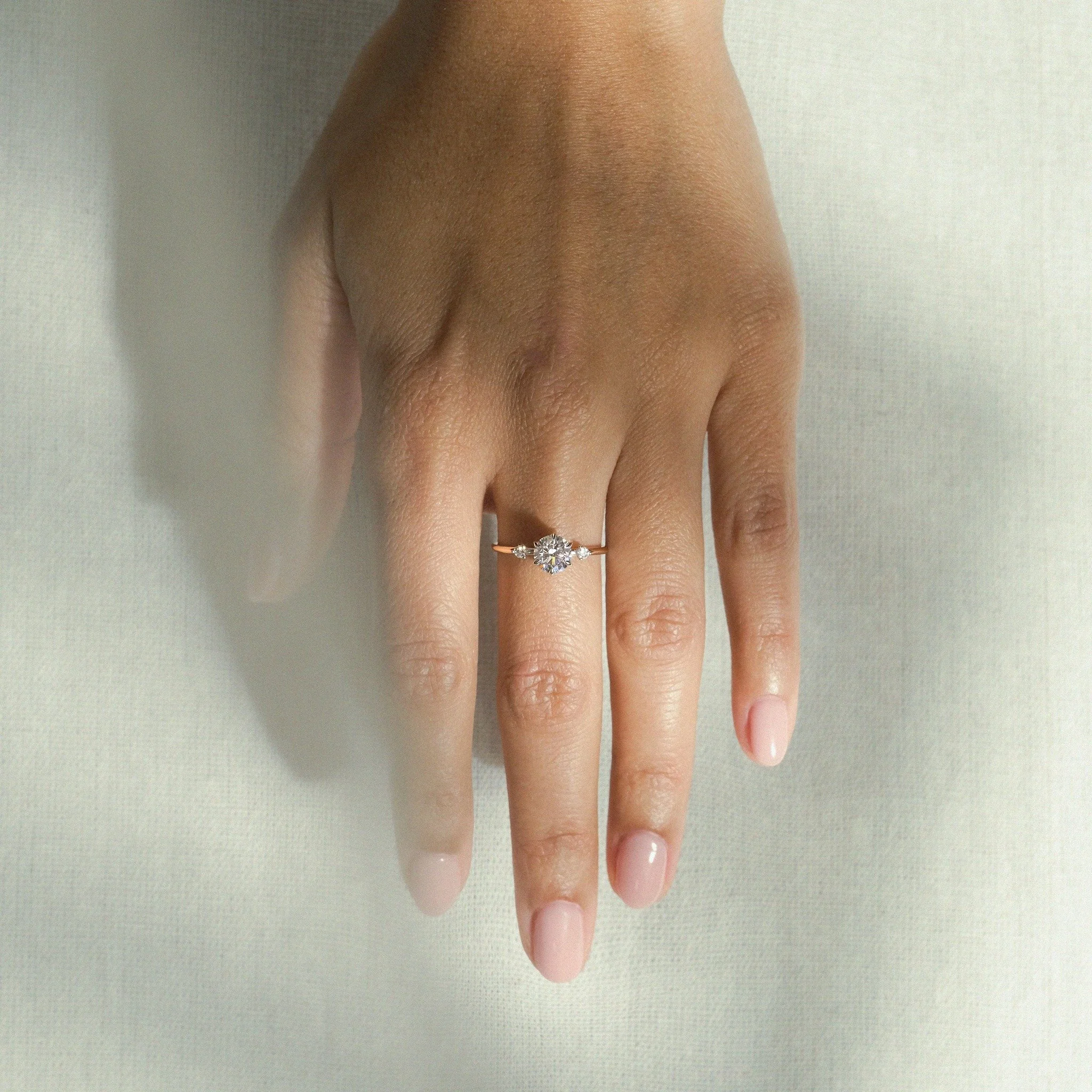 Designed for the modern muse, the Amelia Ring brings a perfect harmony of fluid architectural lines and the delicate floral bloom, setting straight to your hand. Featuring a 1.00ct round brilliant-cut diamond and a rhythmic, airy band, she is a maste