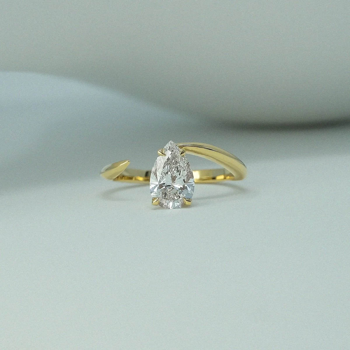 Tear drop alternative engagement ring in 18ct yellow gold architectural smooth open-ended design with pear-cut white diamond from EDXU bespoke jeweller London