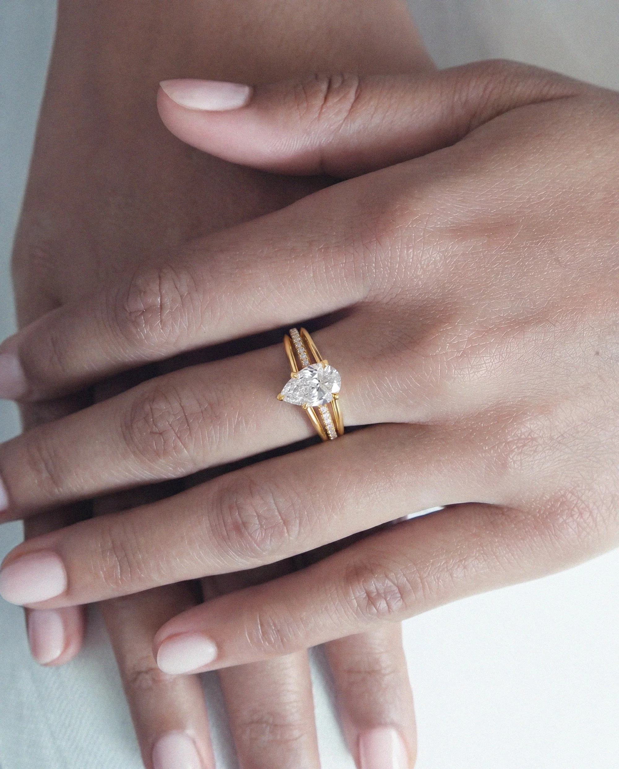 Maeve modern alternative engagement ring features a centre pear-cut diamond with architectural 3-band design with small diamond pave from EDXU bespoke jeweller London editorial photo