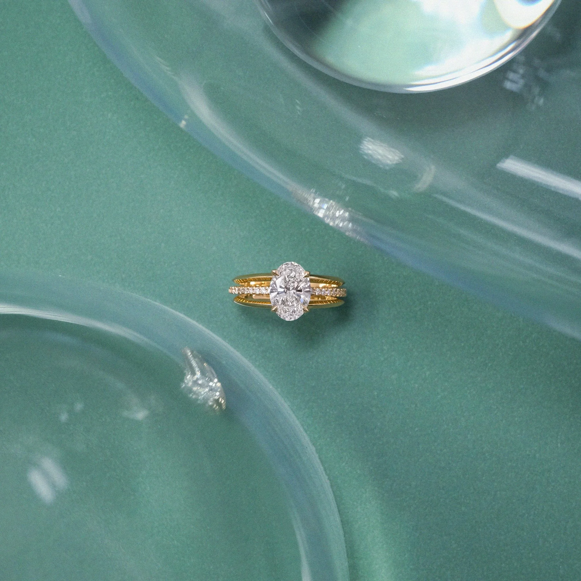 Maeve modern alternative engagement ring features a centre oval-cut diamond with architectural 3-band design with small diamond pave on green paper with glass set from EDXU bespoke jeweller London