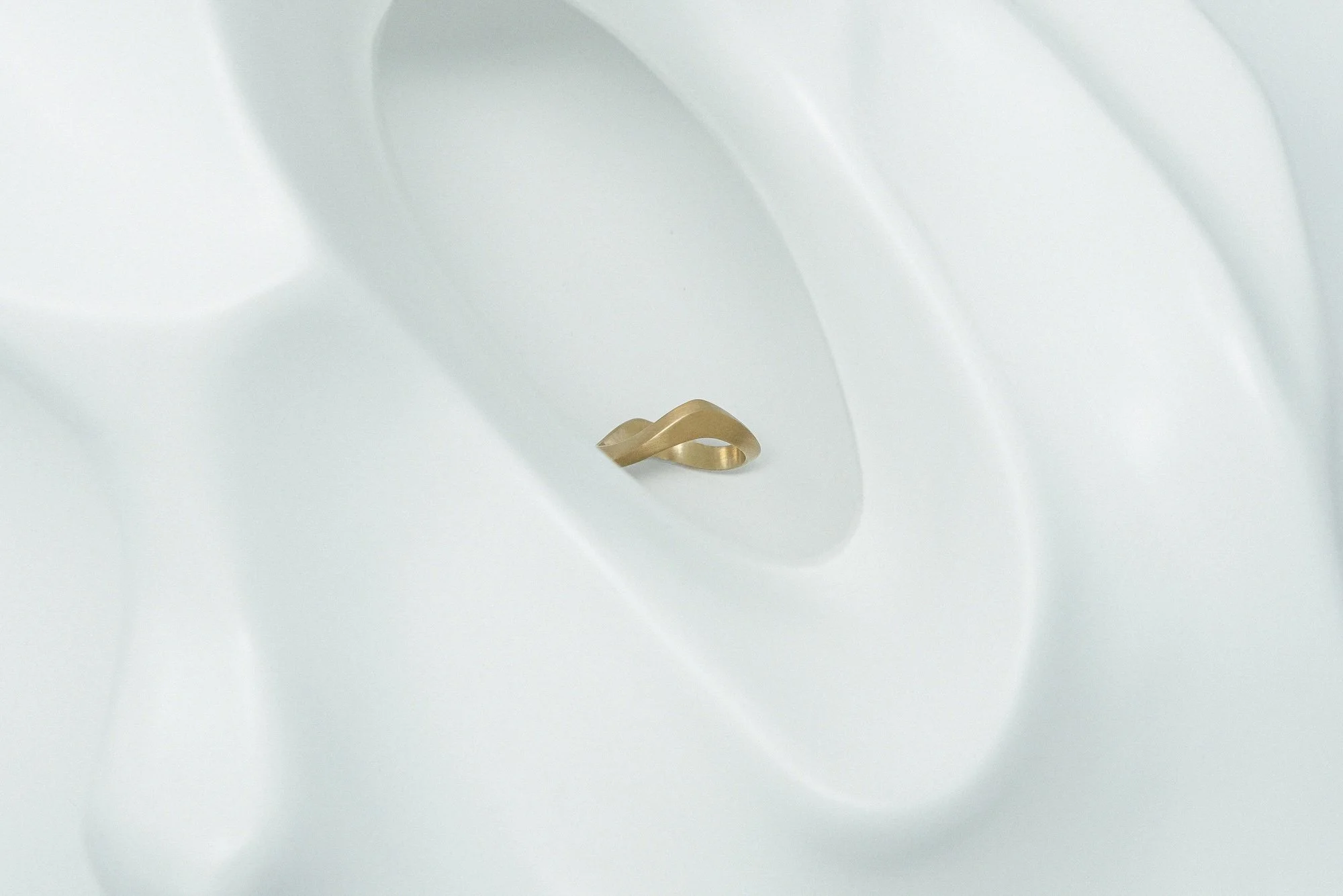architectural wavy sand ring in 18ct matte yellow gold on abstract background lifestyle EDXU London