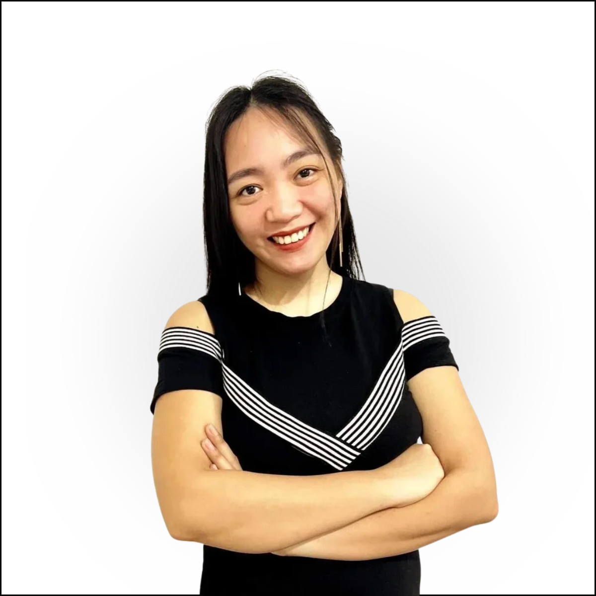 A young woman with black hair, smiling, wearing a black shirt with white striped cold shoulder cutouts, standing against a plain white background.