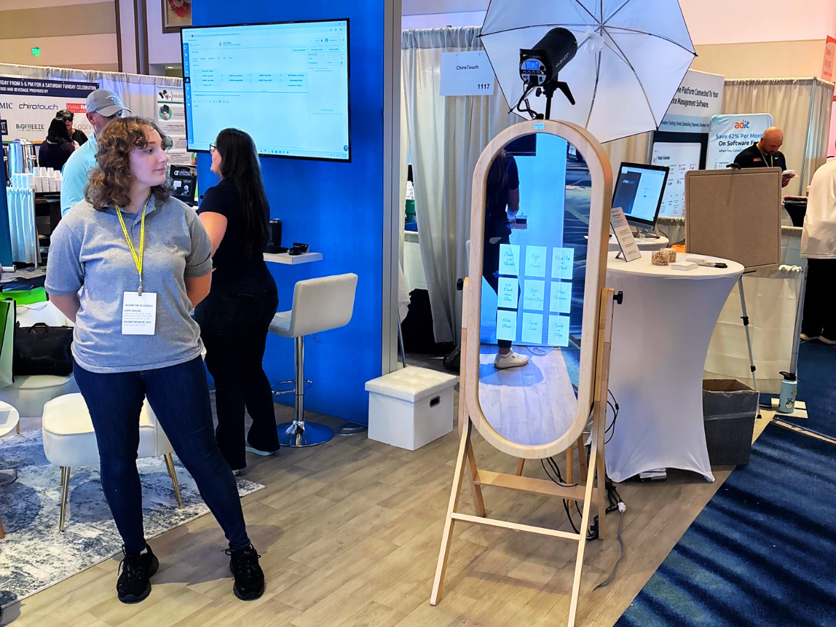 AI photo booth station with a mirror screen and softbox lights at a trade show booth