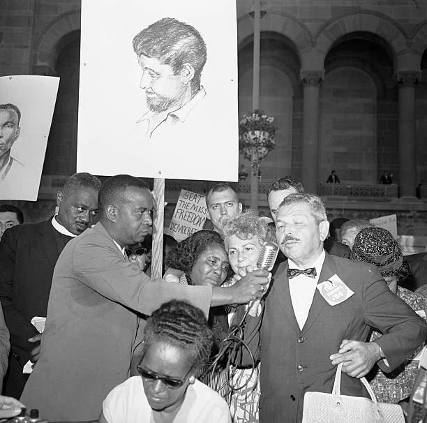 MFDP co-founders (l) Aaron Henry, (seated) Ella Baker and (center) Fannie Lou Hamer with Anne and Nathan Schwerner on the Boardwalk during the Democratic National Convention. The Schwerner's son, Michael (on poster) was murdered with two others in Mi