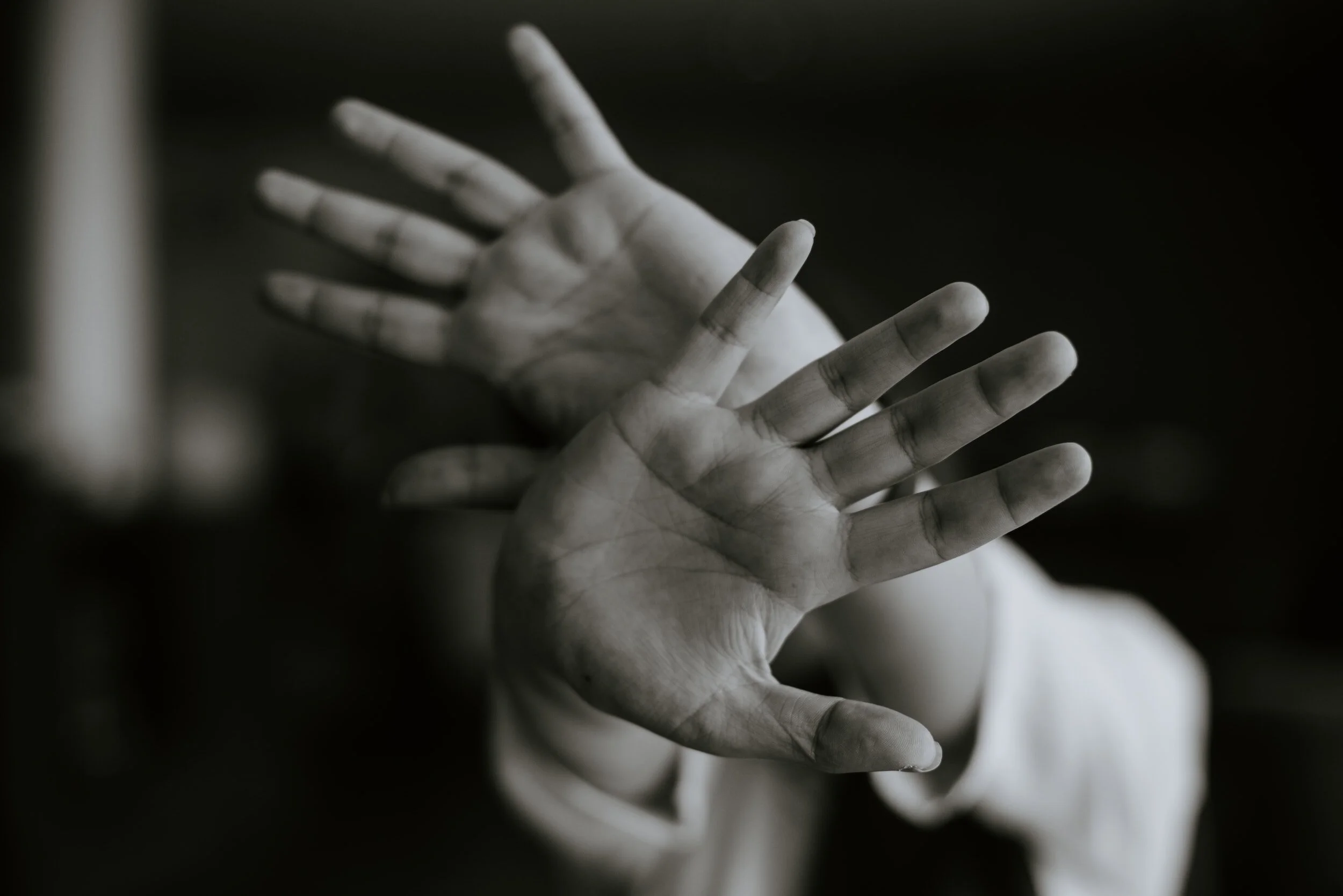 Black and white photo of two hands held up in front of a dark background.